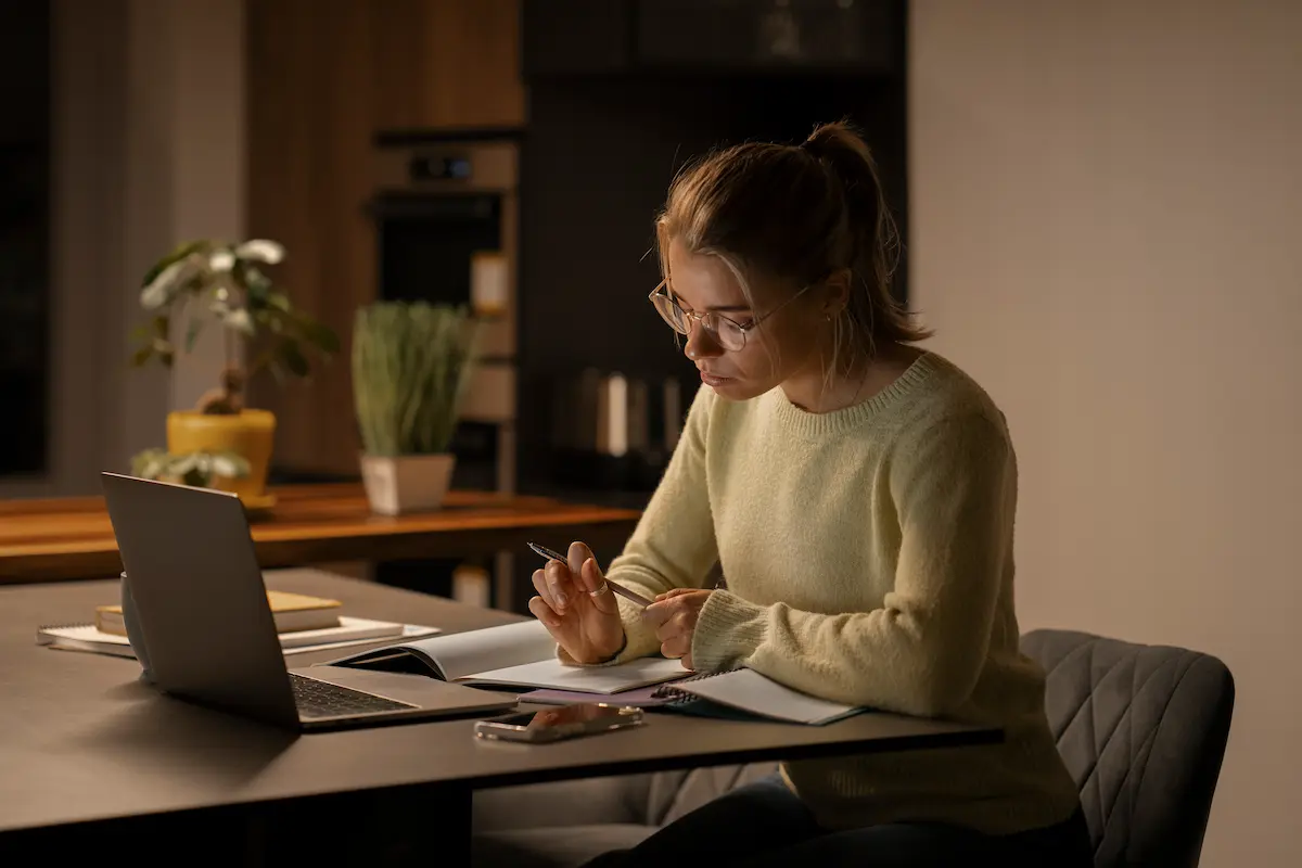 Estudante acompanha aulas de graduação EAD pelo notebook e faz anotações em casa.