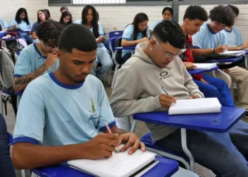 Imagem ilustrativa de estudantes do ensino médio realizando atividades em uma sala de aula.
