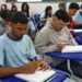 Imagem ilustrativa de estudantes do ensino médio realizando atividades em uma sala de aula.