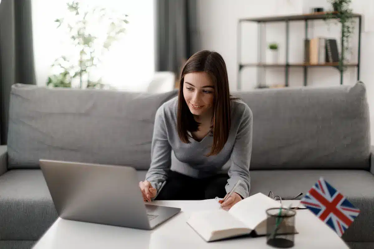 Pessoa estudando inglês em casa com notebook e materiais de apoio para acelerar o aprendizado do idioma.