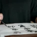 Pessoa praticando a escrita japonesa com pincel e tinta sobre papel, representando o aprendizado do idioma japonês e seus benefícios profissionais.