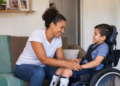 Mãe cuida do filho com deficiência em casa, representando mães atípicas.