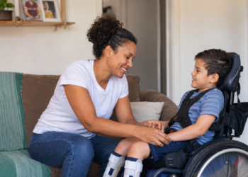 Mãe cuida do filho com deficiência em casa, representando mães atípicas.