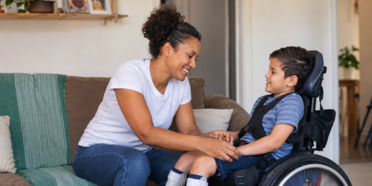Mãe cuida do filho com deficiência em casa, representando mães atípicas.