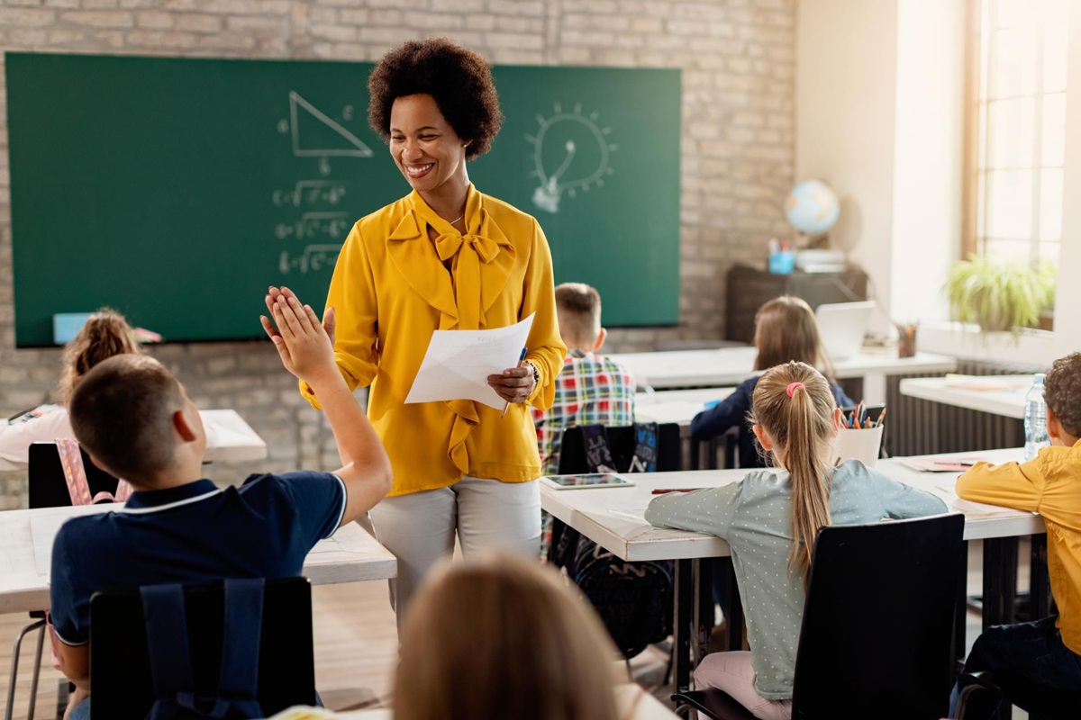 Imagem ilustrativa de professora conduzindo atividade com estudantes sentados nas carteiras, em referência aos requisitos para concorrer às vagas de mestrado do MEC e da Capes