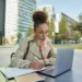 Estudante faz anotações enquanto utiliza um notebook em ambiente universitário.
