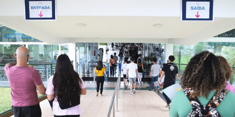 Estudantes com mochilas caminhando em direção à entrada de um prédio de campus universitário, em imagem ligada à ampliação de vagas nas universidades federais.