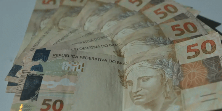 Imagem ilustrativa de várias cédulas de real espalhadas com destaque para uma nota de cem reais, ao lado da inscrição Abono Salarial PIS/Pasep, representando o pagamento do benefício