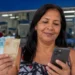 Mulher consulta o celular enquanto segura dinheiro, representando os pagamentos dos benefícios do INSS referentes a agosto e a consulta de informações pelo Meu INSS e pelo telefone 135.