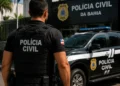 Policial civil em frente a viatura da Polícia Civil da Bahia representando o concurso PC BA para Investigador.