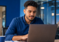 Profissional utiliza notebook em escritório enquanto mantém perfil ativo no LinkedIn.