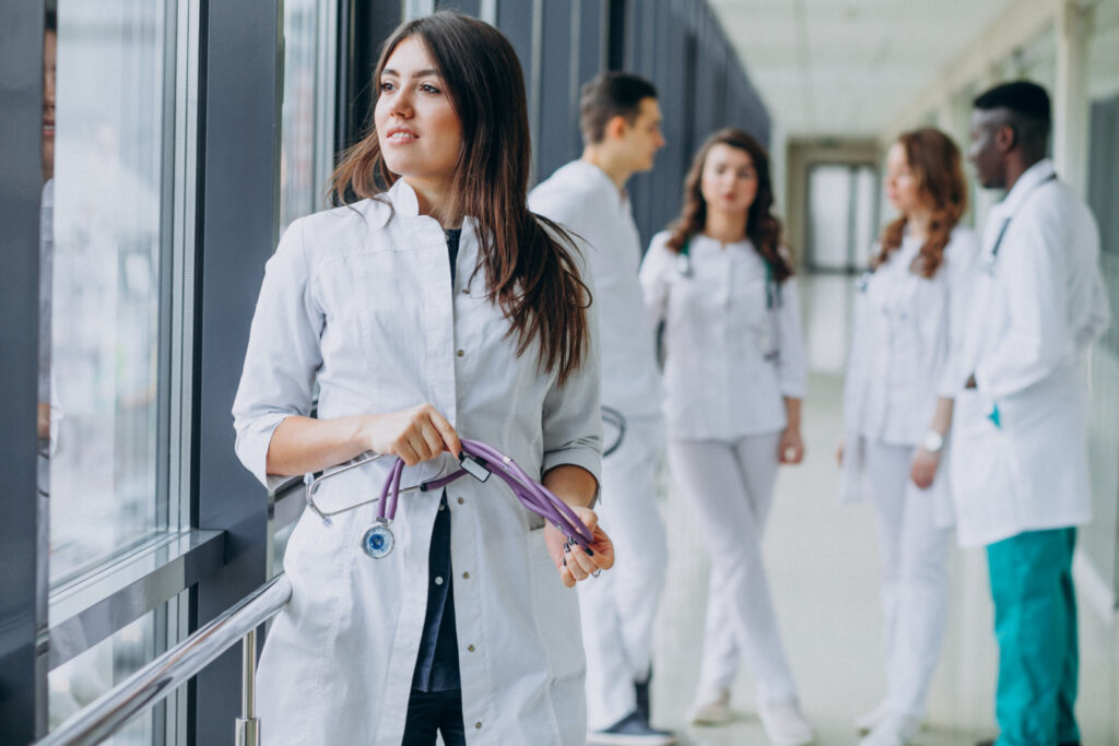 Imagem ilustrativa de estudantes de medicina de jaleco branco reunidos no corredor de uma unidade de saúde, em referência à situação de quem foi inscrito e ficou sem habilitação no Enamed