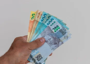 Mão segurando cédulas de real representa a liberação do saque-aniversário do FGTS para trabalhadores nascidos em setembro.