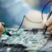 Técnico realizando manutenção em placa de notebook durante reparo de componentes eletrônicos.