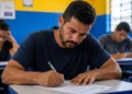 Estudante adulto escrevendo durante prova do Encceja 2026 em sala de aula