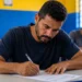Estudante adulto escrevendo durante prova do Encceja 2026 em sala de aula
