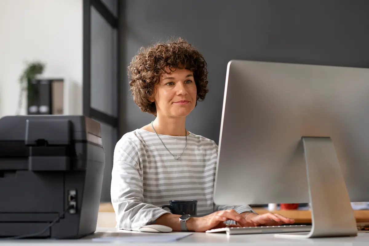 Profissional utilizando computador no escritório, representando planejamento e organização para uma transição de carreira segura.
