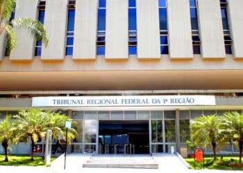 Fachada do prédio do Tribunal Regional Federal da 1ª Região, com o letreiro azul na entrada, palmeiras e escadaria de acesso, referência à decisão da Justiça Federal que suspendeu as punições do órgão de educação