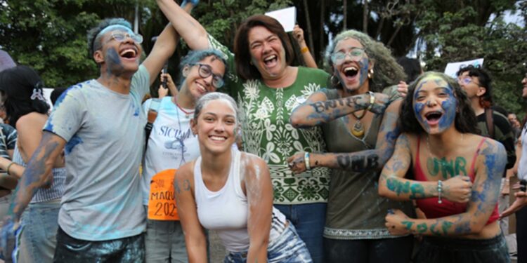 Grupo de estudantes calouros da UnB comemorando ao ar livre, cobertos de tinta azul, em referência à mudança na regra de ingresso na graduação que amplia o uso do Sisu
