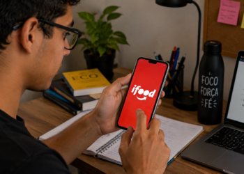 Estudante acessa o aplicativo do iFood pelo celular durante rotina de estudos.