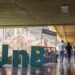 Letreiro tridimensional com a sigla UnB instalado em corredor coberto do campus da Universidade de Brasília, com estudantes caminhando ao fundo.