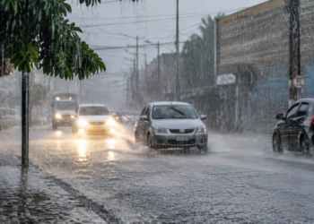 Chuva intensa em rua movimentada, representando o significado do verbo chover em português.