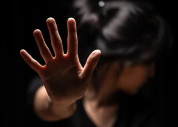 Mulher ergue a mão em gesto de proteção, representando a violência contra mulheres e o vicaricídio.