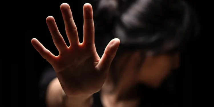 Mulher ergue a mão em gesto de proteção, representando a violência contra mulheres e o vicaricídio.