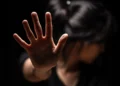 Mulher sinaliza pedido de ajuda em representação ao combate ao assédio e à violência contra mulheres.