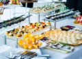 Bufê com seleção variada de aperitivos gourmet em evento, simbolizando a dúvida entre "buffet” e “biffet.