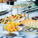 Bufê com seleção variada de aperitivos gourmet em evento, simbolizando a dúvida entre "buffet” e “biffet.