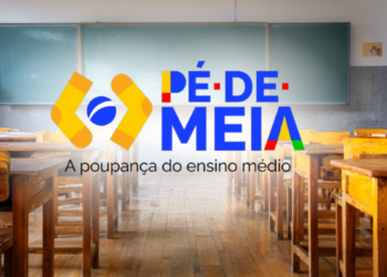 Sala de aula vazia com carteiras de madeira e logo do Pé-de-Meia ao centro.