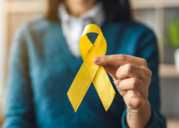 Pessoa segura laço amarelo simbolizando conscientização sobre prevenção ao suicídio.