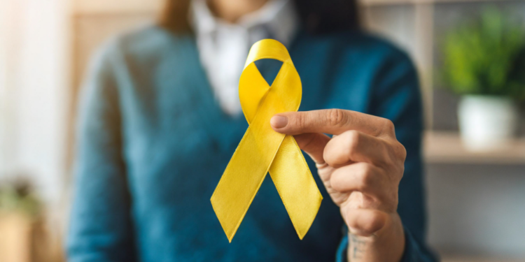 Pessoa segura laço amarelo simbolizando conscientização sobre prevenção ao suicídio.