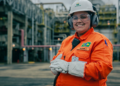 Funcionária da Petrobras com uniforme laranja em área industrial.