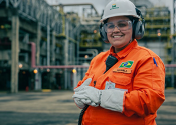 Funcionária da Petrobras com uniforme laranja em área industrial.