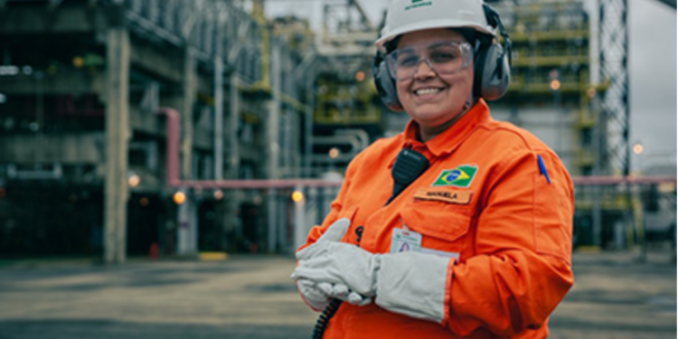 Funcionária da Petrobras com uniforme laranja em área industrial.