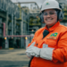 Funcionária da Petrobras com uniforme laranja em área industrial.