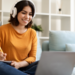 Jovem estudando online com fones de ouvido e anotando no caderno.