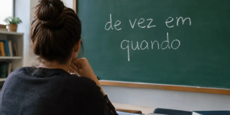 Jovem de costas, em ambiente de estudos, observa um quadro verde com a expressão “de vez em quando” escrita em giz.