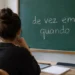 Jovem de costas, em ambiente de estudos, observa um quadro verde com a expressão “de vez em quando” escrita em giz.
