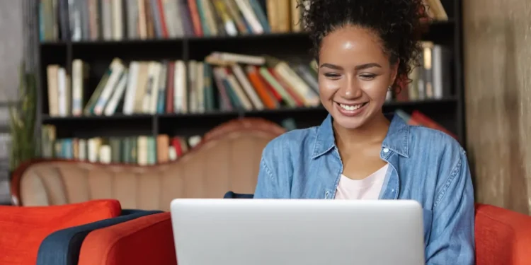 Jovem estudante usando notebook para representar as inscrições do Estágio Corporativo Itaú 2026.
