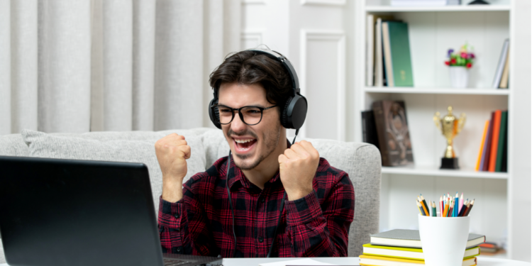 Jovem comemorando conquista online em ambiente de estudos.