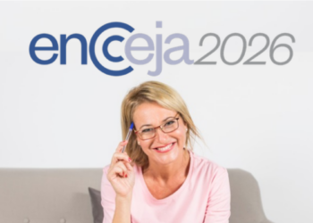 Mulher loira de óculos, sorrindo e segurando caneta azul e logo do Encceja encima.