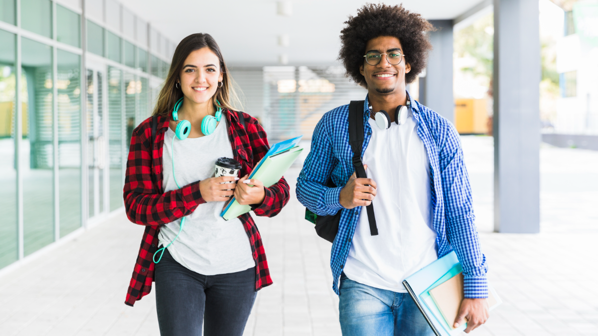Jovens universitários sorrindo com mochilas e materiais na faculdade.