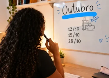 Jovem planejando viagens em outubro com quadro branco e datas destacadas.
