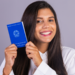 Jovem sorrindo exibe Carteira de Trabalho brasileira em fundo neutro.