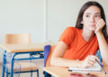 Estudante pensativa em sala de aula vazia.