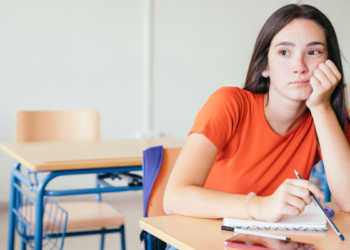 Estudante pensativa em sala de aula vazia.