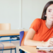Estudante pensativa em sala de aula vazia.